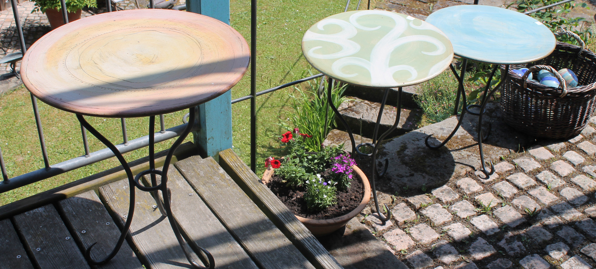 Drei runde Terrassentische mit Tischplatten aus farbig glasierter Keramik